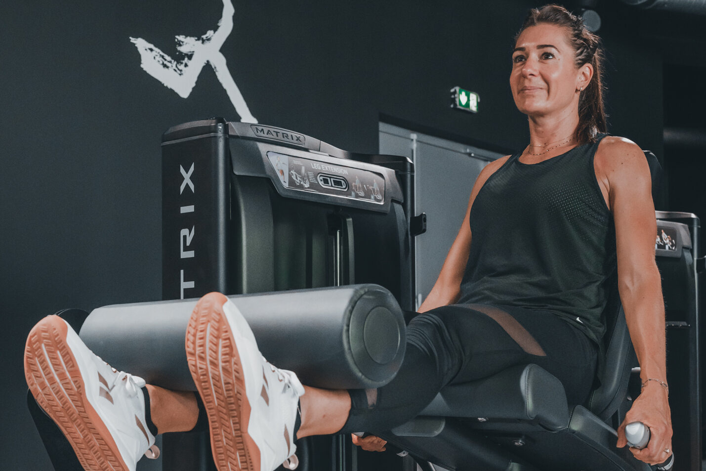 Salle de sport avec une participante en pleine séance de fitness full body.